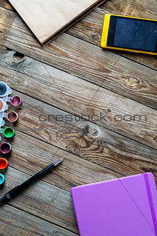 Watercolors, color pencils and sketchbook on wooden table. Flat lay photo with empty space for logo, text.