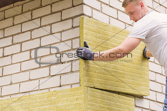 construction worker insulating house facade with mineral rock wo