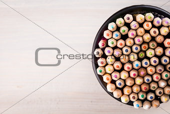 Color pencils in a office bin on wooden background