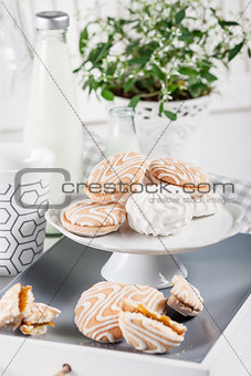Sweet cookies on white tray with cups of coffee with green and w
