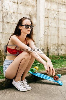 Cute hipster girl in bikini with skateboard.