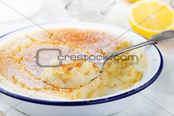 Lemon pudding cake with fresh lemons on a white wooden background.