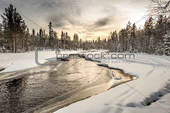Snow-covered riverbank under the sunset sky. Northern Karelia. Russia.