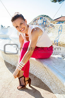 Woman adjusting shoe while sitting on trencadis style bench