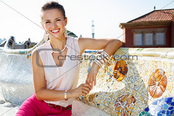 Smiling woman sitting on the famous trencadis style bench