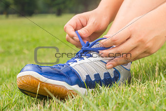 Girl is tying shoes laces for jogging at park.
