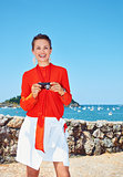 Happy woman with photo camera standing in front of lagoon