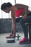 Fitness woman taking dumbbell from the floor in urban loft gym