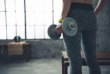 Closeup on fitness woman holding dumbbell in urban loft gym