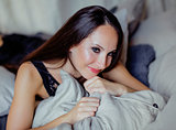 pretty young brunette woman in bedroom interior smiling