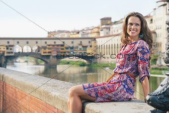 Smiling woman sitting on the embankment near Ponte Vecchio
