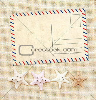 Four starfishes and old postcard on canvas texture