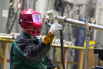 Industrial worker welding in metal factory.