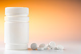 Plastic pill bottle and heap of round white pills