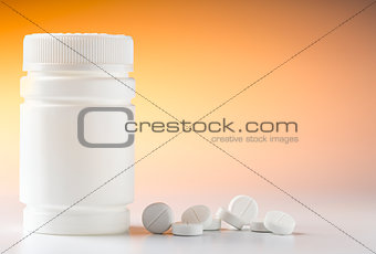 Plastic pill bottle and heap of round white pills