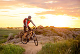 Cyclist Riding the Bike on Mountain Rocky Trail at Sunset