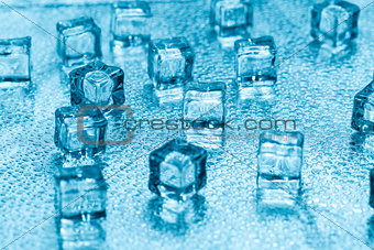 Melting transparent blue ice cubes on glass