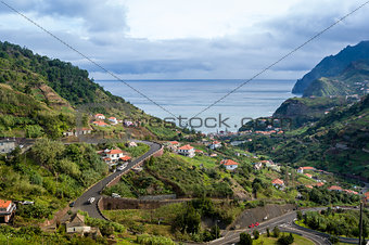 Typical landscape of Madeira island, serpentine mountain road, houses on the hills and ocean view