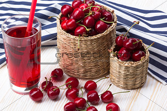 Cherry baskets and juice on wooden background
