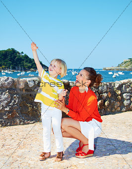 Happy daughter showing something to mother in front of lagoon