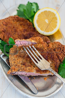 Piece of beef schnitzel on a fork.
