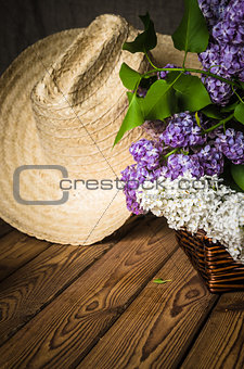 Still-life with a bouquet of lilacs and a straw hat