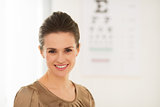 Happy young woman in front of Snellen chart