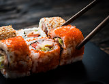 closeup of sushi rolls with chopsticks