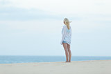 Woman on sandy beach in white shirt.