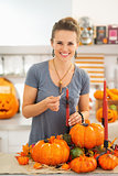 Smiling woman lighting a candle in halloween decorated kitchen