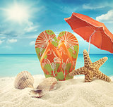 Sandals and starfish with beach umbrella at the ocean