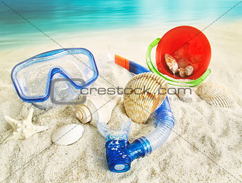 Water goggles and beach toys in the sand