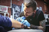 Beautiful tattooist does the tattoo