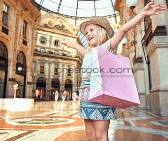 Happy fashion girl with pink shopping bag in Galleria rejoicing