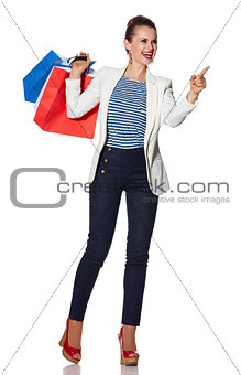 Smiling young woman with shopping bags pointing on copy space