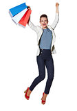 Happy woman with shopping bags jumping against white background