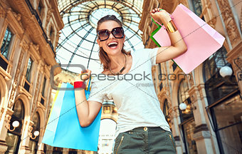 Woman with shopping bags in Galleria Vittorio Emanuele rejoicing