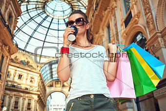 Fashion monger with shopping bags and coffee cup in Galleria