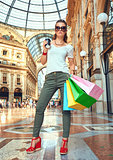 Fashion monger in eyeglasses with shopping bags and coffee cup