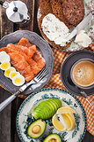 Breakfast with salmon, eggs, avocado, bread, cheese and coffee