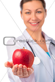 Smiling doctor holding a red apple in the palm