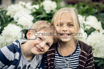 Beautiful blond girl and adorable boy looking at the camera and smiling.
