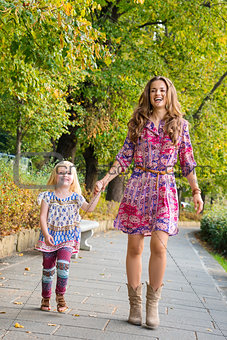 Full length portrait of mother and daughter walking at the park
