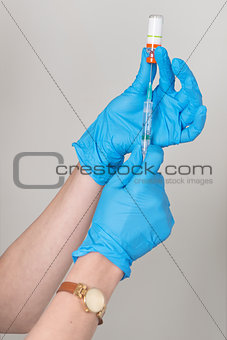 Hands in rubber gloves gather medicine in the syringe