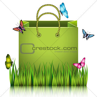 Green paper shopping bag on the meadow grass.
