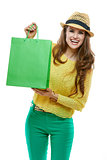 Portrait of smiling woman in hat showing green shopping bags