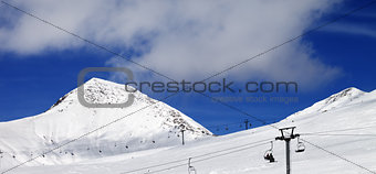 Panoramic view on chair-lift and ski slope at sun day