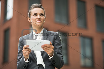 Modern business woman with tablet PC against office building