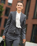 Happy business woman with briefcase walking at office district