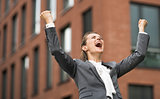 Happy modern business woman against office building rejoicing